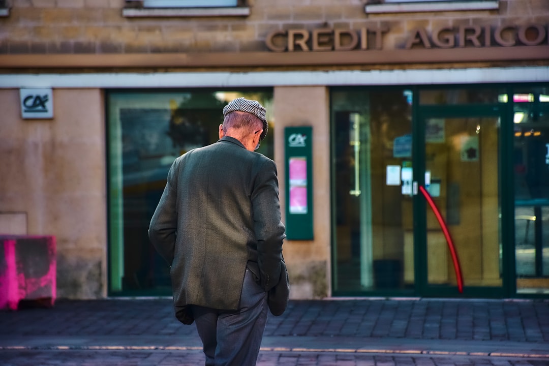 man-walks-towards-a-credit-agricole-bank-entrance-gumdvly-lf4